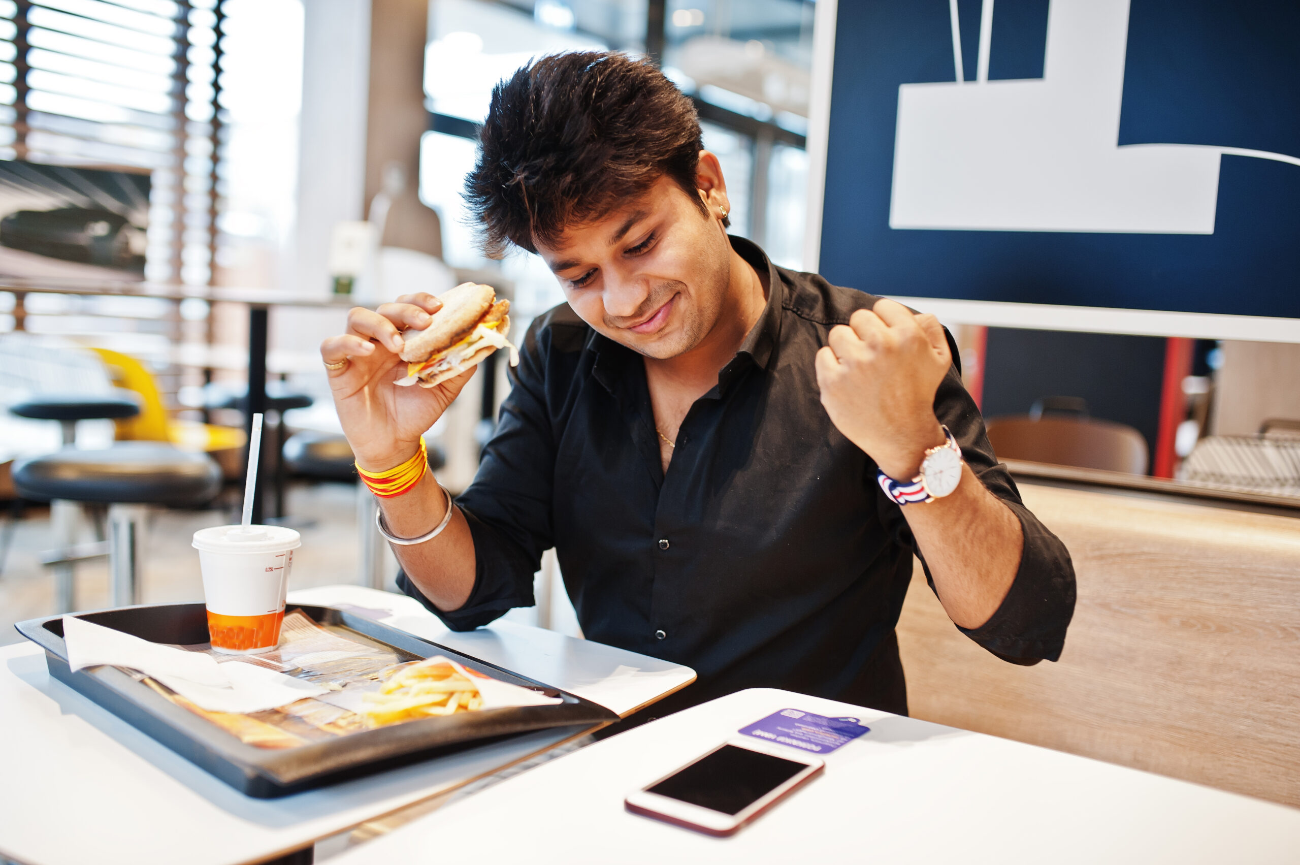 young man enjoying a burger meal at the best food joint in gurgaon at the vensej mall
